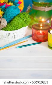 The white basket crochet fabric and colored yarn. Candles in candlesticks color. Background of white wood. Tea and cakes. Crochet hooks. - Shutterstock ID 506910283