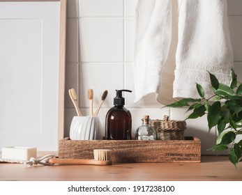 White bath background front view with cosmetic bottle, bath accessories, toothbrushes in a glass and houseplants on wood shelf and wall tiles. Front view. Copy space