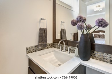 White Bathroom Features A Nook Filled With A Brown Vanity With Rectangular Sink And A Mosaic Tiled Backsplash Under A Large Framed Mirror. Northwest, USA