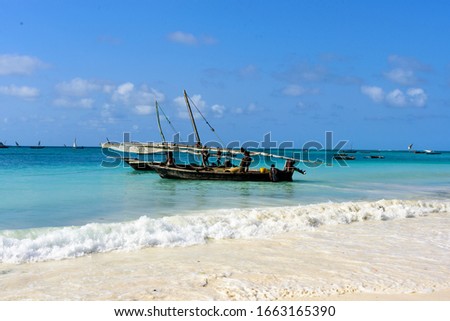 White beach and deep blue sea with fisherboats at the West coast of Sansibar