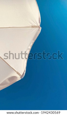 White beach umbrella and blue sky. Colorful wallpaper and screensaver for your phone. Bottom view of a beach umbrella. Art photo, abstraction.