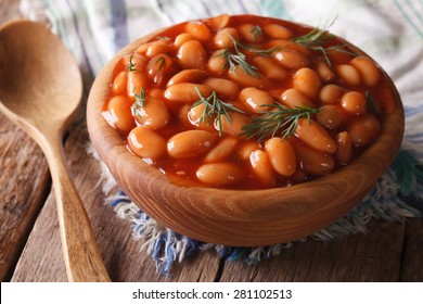 white beans in tomato sauce in a wooden bowl closeup. horizontal