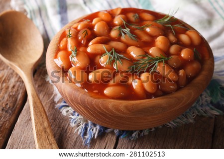 white beans in tomato sauce in a wooden bowl closeup. horizontal
