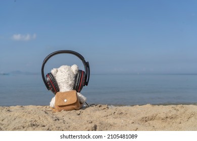 white bear wearing headphone listen music relaxing on the beach . Summer vacation or valentine concept.