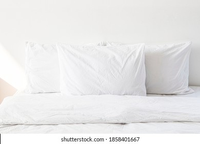 White bed linen on a bed in a white bedroom - Shutterstock ID 1858401667