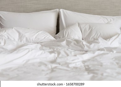 White Bed Made-up With Wrinkled Bed Sheets After Sexual Night. White Bedding Sheets After Wake Up In The Morning.White Cotton Sheet Texture Or Background. Messy Bed After Funny Night. 