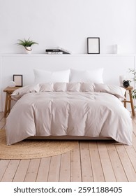 White bed with two handcrafted bedside tables in a bedroom with a modern interior and wooden floor. Fluffy duvet and two white pillows is on the bed. Horizontal front view photo. Suitable for mockup