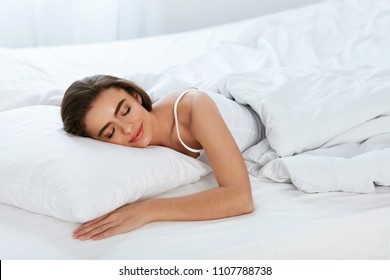 Белое постельное белье. Женщина спит на матрасе с подушкой.