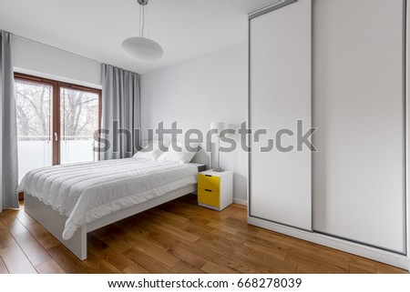 White bedroom with double bed and sliding door wardrobe