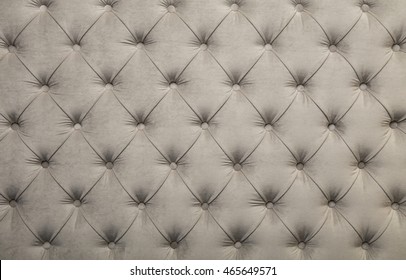 White beige velvet capitone textile background, retro Chesterfield style checkered soft tufted fabric furniture diamond pattern decoration with buttons, close up