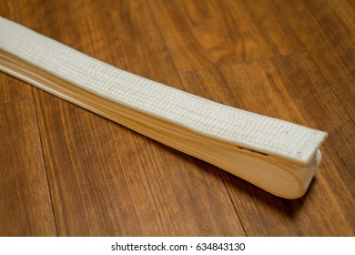 A White Belt (Karate, Judo, Kenpo, Jiu-Jitsu, Budo, Martial Arts, Taekwondo) Placed On The Wood Floor