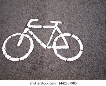 White Bicycle Symbol On The Black Road In The Park, Paved Lanes For Cyclists On The Background. With Space To Copy