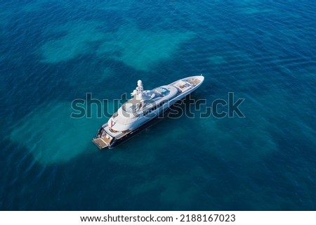 White big yacht for a billionaire anchored on a transparent aerial view. Mega yacht on blue top view. Modern big white yacht on transparent water top view.