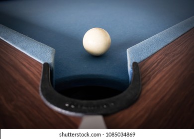 White Billiard Ball Close To Billiard Pocket On Blue Pool Table