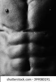 White and black background of handsome bare male sensual strong wet torso with muscular cool abdominal and pectoral muscles closeup, vertical picture