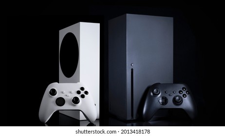 White and black game consoles and controllers with black background - Shutterstock ID 2013418178