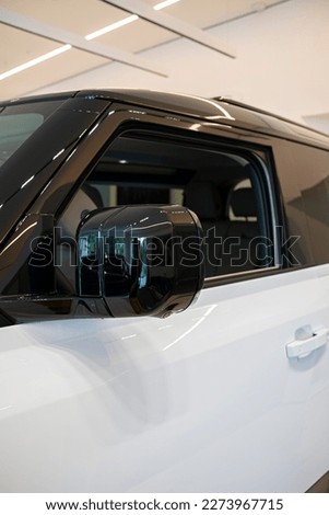 White and black Land Rover Defender side mirror, photographed in a dealership