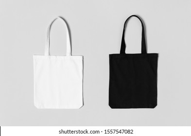 White and black tote bags mockup on a grey background.