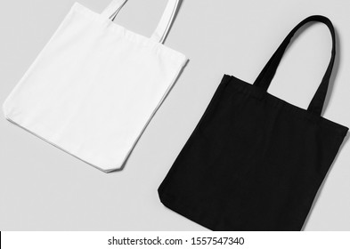 White and black tote bags mockup on a grey background.