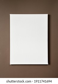 White blank canvas weighs on a dark wall. Mockup poster to replace your design. Material for painting with oil paints and acrylic. Close-up photo.