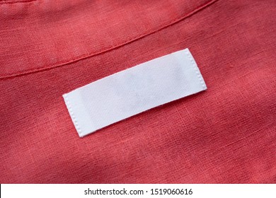 White Blank Clothing Tag Label On Red Linen Shirt Fabric Texture Background