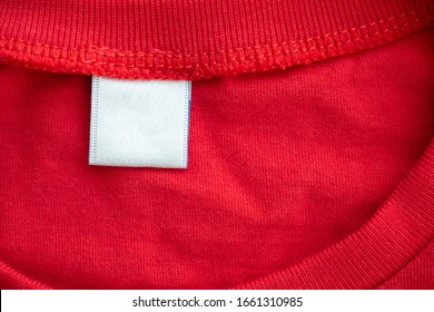 White Blank Clothing Tag Label On New Red Cotton Shirt Fabric Texture Background