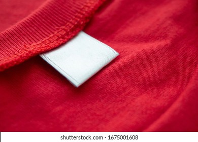 White Blank Clothing Tag Label On New Red Cotton Shirt Fabric Texture Background