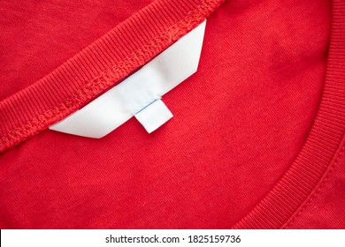 White Blank Clothing Tag Label On New Red Cotton Shirt Fabric Texture Background