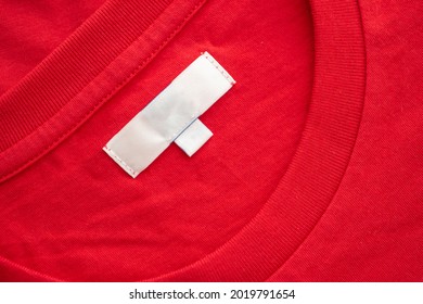 White Blank Clothing Tag Label On New Red Cotton Shirt Fabric Texture Background