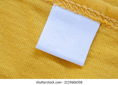 White blank clothing tag label on new yellow shirt background - Shutterstock ID 2119606358