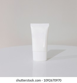 White Blank Cosmetic Tube For Gel And Lotion. Mock Up Photoshoot On Top Of White Table And White Wall Background