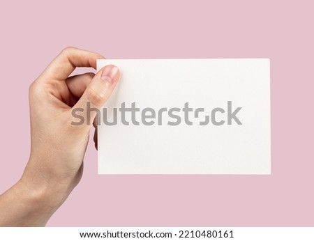 White blank empty postcard mockup in hand on pink background. High quality photo