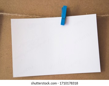 White blank with empty space for text pin up with blue clothespins on brown background. Bussiness message with free space for text. Stiker note in office. Paper square for notes. 