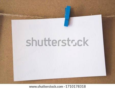 White blank with empty space for text pin up with blue clothespins on brown background. Bussiness message with free space for text. Stiker note in office. Paper square for notes. 