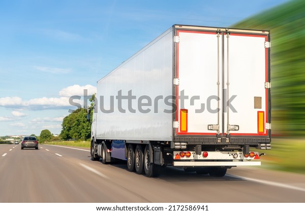 White blank modern delivery big shipment cargo\
commercial semi trailer truck moving fast on motorway road city\
urban suburb. Business distribution logistics service. Lorry\
driving highway sunny day