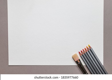 White Blank Page With Watercolor Pencils In Red And Yellow Shades With A Brush