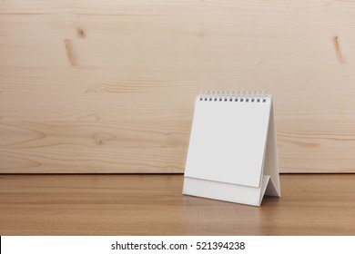 White blank paper desk spiral calendar on wood background.
