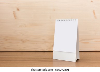 White blank paper desk spiral calendar on wood background.