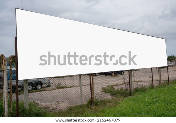 White blank\
poster with mock up fixed on metal fence of used vehicles sales\
market. Second hand auto trade\
concept.