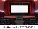 White blank screen in empty movie theater with rows of seats and red interior