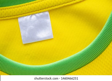 White Blank Textile Clothes Label On Yellow Sport Clothing Fabric Jersey Texture 