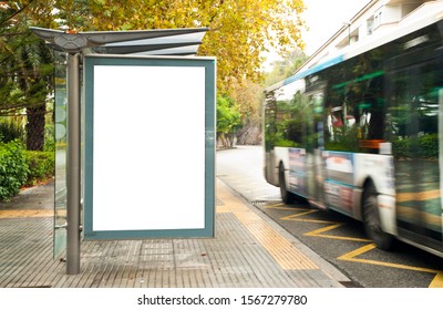 White Blank Vertical Billboard At The Bus Stop On The City Street. In The Background Of Buses And Roads. Sketch. Poster On The Street Next To The Road.