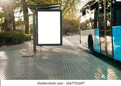 White Blank Vertical Billboard At The Bus Stop On The City Street. In The Background Of Buses And Roads. Sketch. Poster On The Street Next To The Road