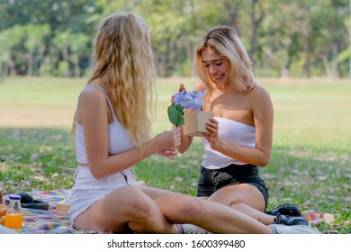 White blond girl get gift from her friend with surprise and happy action in the garden with day light. - Powered by Shutterstock