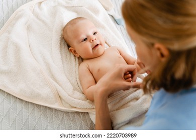 White Blonde Woman Playing And Swaddling Her Baby In Bedroom At Home