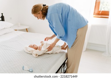 White Blonde Woman Wearing Shirt Swaddling Her Baby In Bedroom At Home