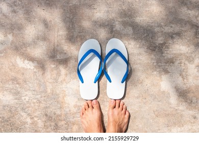 white and blue color slipper on concrete floor in a shade, casual shoes and footwear, bear foot of a person
