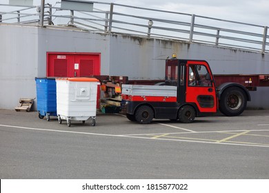 White & Blue Commercial Rubbish Bins Waiting For Collection Near Small Pulling Truck In Car Park. Space To Add Text On Road Surface In Front Of The Big Bins For Industrial, Waste Management Concept.