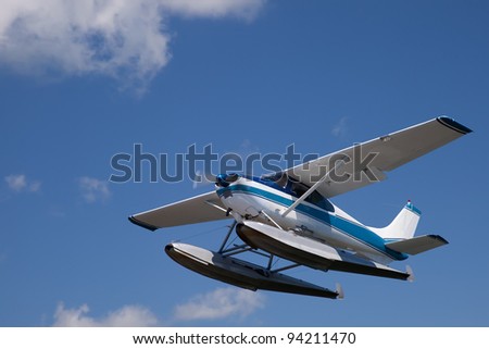 White and blue float plane against cloudy sky