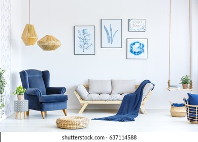 White and blue living room with sofa, armchair, lamp, posters